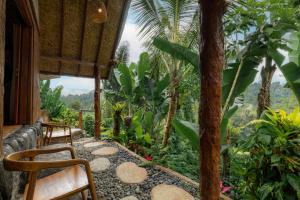a porch with two chairs and a tree at Vana Nugraha Villas in Tampaksiring