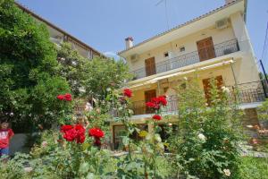 un edificio con flores rojas delante de él en Melifilos, en Agios Ioannis