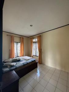 a bedroom with a large bed and two windows at Vila Biru Gundaling Brastagi in Berastagi