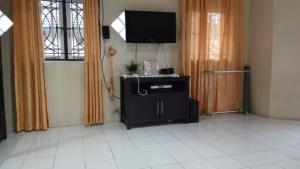 a living room with a tv and a tiled floor at Vila Biru Gundaling Brastagi in Berastagi