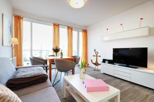 a living room with a couch and a tv and a table at Eicher Ferienwohnungen Warnemünde in Warnemünde