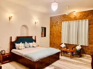 a bedroom with a bed and a table and a window at The WildRocks Jawai in Nāna