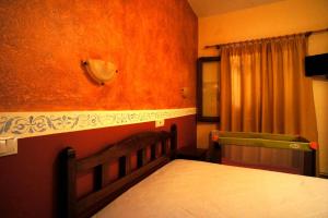 a bedroom with a bed with an orange wall at Melifilos in Agios Ioannis Pelio
