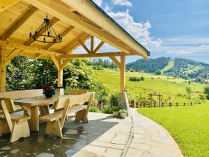 a wooden pergola with a table and benches at Osada Snozka - domki w górach z balią i kominkiem in Kluszkowce
