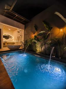 a bathroom with a swimming pool with a tub and a sink at Agarra Villa in Yogyakarta