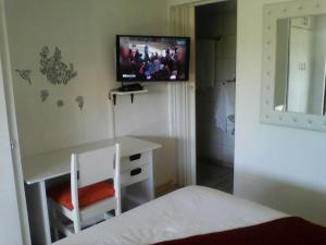 a bedroom with a desk and a tv on the wall at Aliwal Villa Guest Lodge in Aliwal North