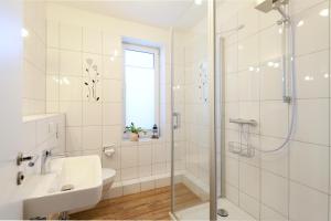a white bathroom with a shower and a sink at Eicher Ferienwohnungen Warnemünde in Warnemünde +92 photos