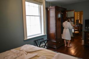 a woman standing in a bedroom looking in a mirror at The Marshall House, Historic Inns of Savannah Collection in Savannah