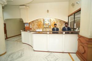 two men in suits sitting at a counter in a room at HOTEL ABHISHEK, Shirdi in Shirdi