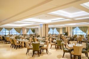 a dining room with tables and chairs and windows at Finda Hotel in Medina