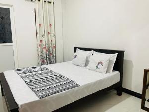 a bed with white sheets and pillows in a room at Kumara Guest House Dambulla in Dambulla