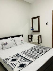 a bed with a black and white comforter and a mirror at Kumara Guest House Dambulla in Dambulla