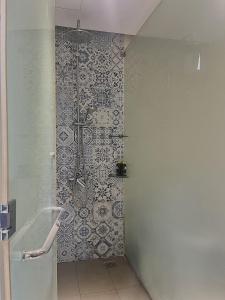 a bathroom with a shower with a tile wall at Oceanami Resort beach club in Long Hai
