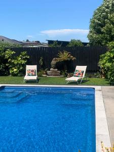two chairs and a swimming pool in a yard at Parkside Boutique Lodge in Rotorua
