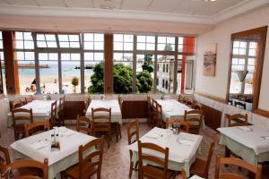 a restaurant with tables and chairs and a view of the beach at Hostal Buenavista in San Ciprián