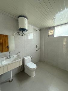 a white bathroom with a toilet and a sink at Vezara homestay in Kūfrī