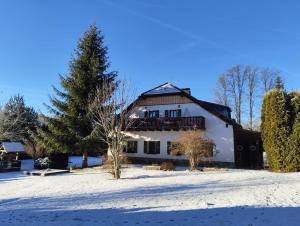a white house in the snow with a tree at Pension Pumperle in Strážný