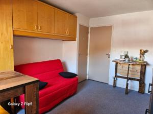 a red couch in a small room with a table at joli studio vue montagne in Allos