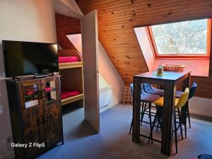 a room with a table and a tv and a bedroom at joli studio vue montagne in Allos