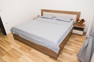 a bedroom with a bed with white sheets and a wooden floor at Apartments Josif in Gevgelija