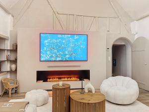 a living room with a fireplace and a tv at Beautiful longere with pool in Courcelles-lès-Gisors