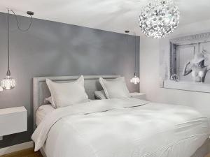 a bedroom with a large white bed and a chandelier at Beautiful longere with pool in Courcelles-lès-Gisors