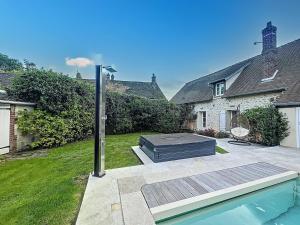 a backyard with a swimming pool and a house at Beautiful longere with pool in Courcelles-lès-Gisors
