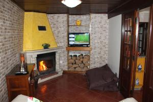 a living room with a fireplace and a television at Casa D'Aldeia in Geres