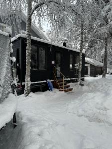 a black cabin in the snow with trees at Santa Elves Cabin in Rovaniemi