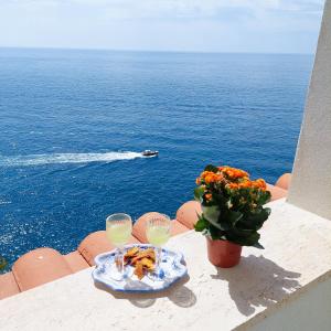 a table with a plate of food and two wine glasses at Casa Gianna New 2026 in Praiano