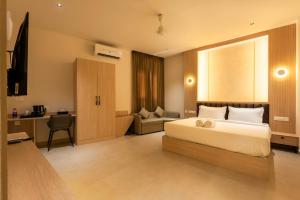 a bedroom with a bed and a desk and a chair at The Continental Suites in Kozhikode +34 photos