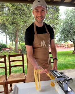 a man standing in a kitchen preparing pasta at Relais Villa La Cappella in Montespertoli