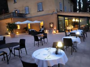 a restaurant with white tables and chairs and a building at Relais Villa La Cappella in Montespertoli