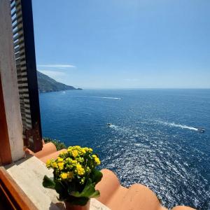 a vase of yellow flowers on a balcony overlooking the ocean at Casa Gianna New 2026 in Praiano