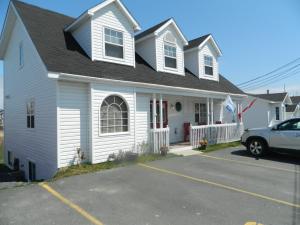 une maison blanche avec une voiture garée devant elle dans l'établissement Whitsha Inn B&B, à Twillingate