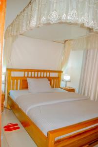 a bedroom with a canopy bed with red slippers on the floor at CLEMENT MOTEL in Rutsiro