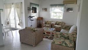 a living room with couches and chairs and a tv at Worthing Beach Apartments in Bridgetown