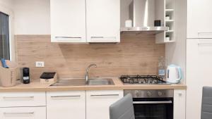 a kitchen with white cabinets and a sink at Maison Studio in Chioggia