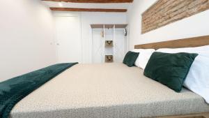 a white bedroom with a large bed with green pillows at Maison Studio in Chioggia