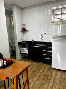 a kitchen with a sink and a table in it at Apartamento 1 quarto, sala e cozinha próximo ao Aeroporto in Vitória +2 photos