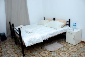 ein Bett mit weißen Laken und Kissen in der Unterkunft LRx in Chimoio