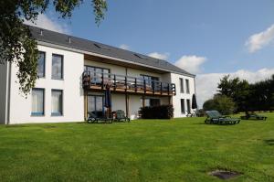 a large white building with benches in a yard at Le Panorama Nadrin in Nadrin