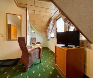 a room with a tv and two chairs and a table at Hotel Berglandstübel in Hammerbrücke