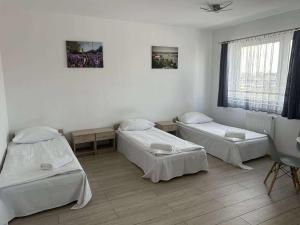 a room with three beds and a window at VESTA Apartamenty P23 in Szczecin