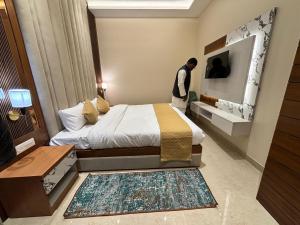 a man standing next to a bed in a room at Hotel Ramya in Varanasi