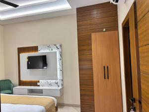 a bedroom with two beds and a tv on the wall at Hotel Ramya in Varanasi