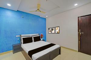 a bedroom with a bed with a blue wall at Hotel O Madhuram Lodge in Siddipet