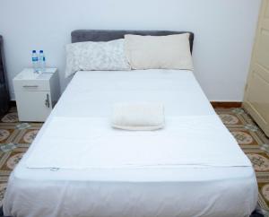 ein weißes Bett mit einem Hut darauf in der Unterkunft LRx in Chimoio