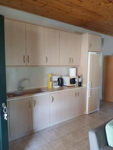 a kitchen with white cabinets and a refrigerator at Lefter's Cottege in Nea Irakleia