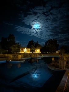 a swimming pool at night with a full moon at Cafour House Siwa - Hot Spring in Siwa